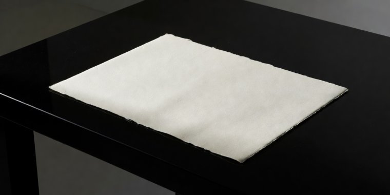 A neutral unbranded credential paper document sitting under clean directional lighting on an obsidian desk